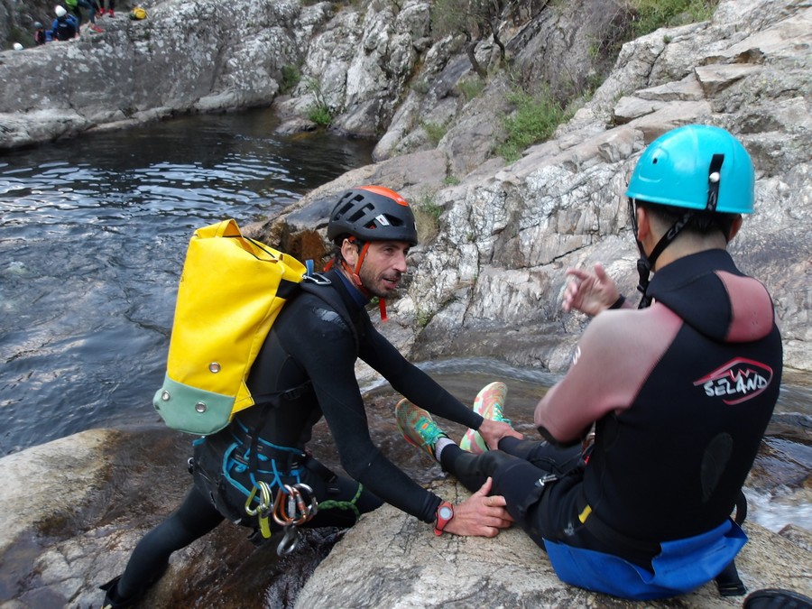 un guide de canyoning, équipé de pied en cap, donnes les indications avant le toboggan