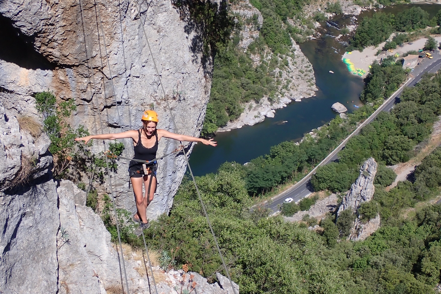 une femme progresse sur un pont de singe, les bras écartés